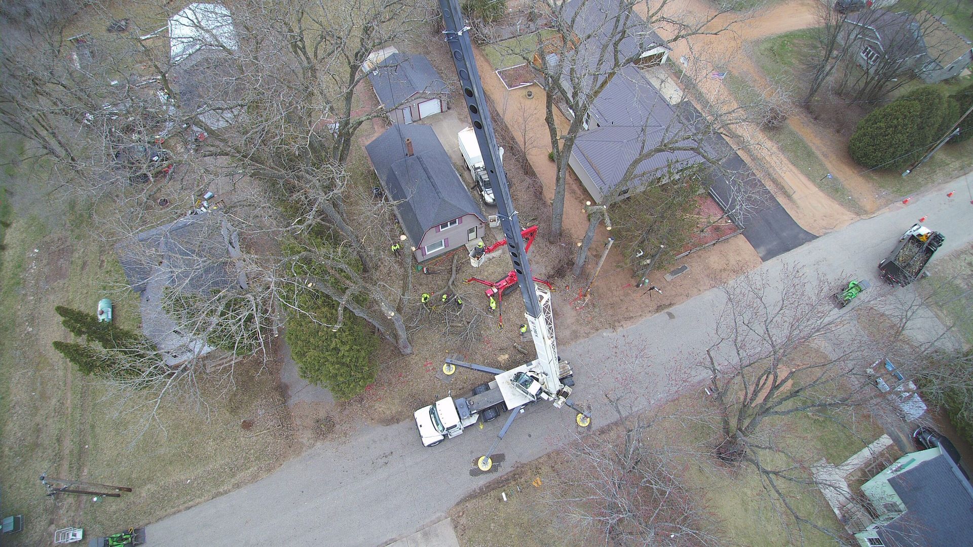 An aerial view of a tree being cut down in a neighborhood.