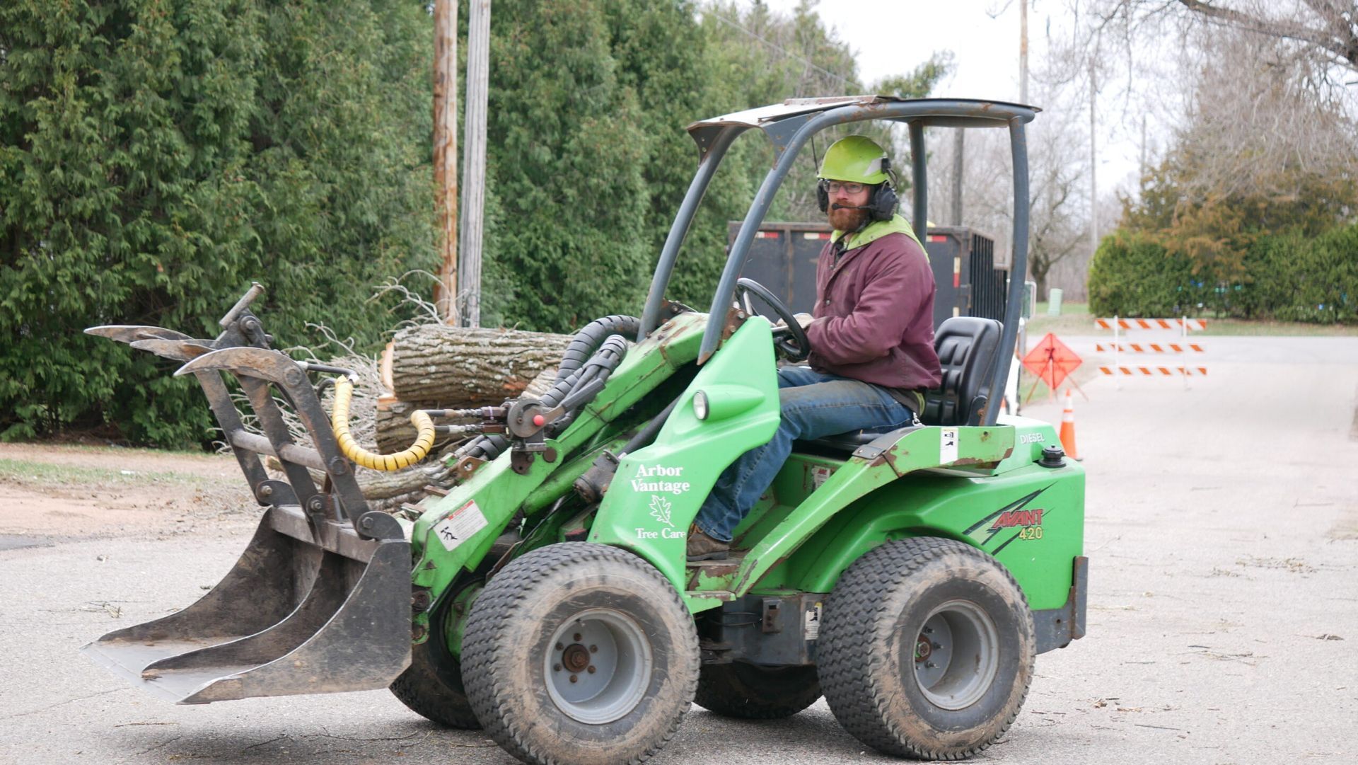 A man is driving a green tractor in a parking lot