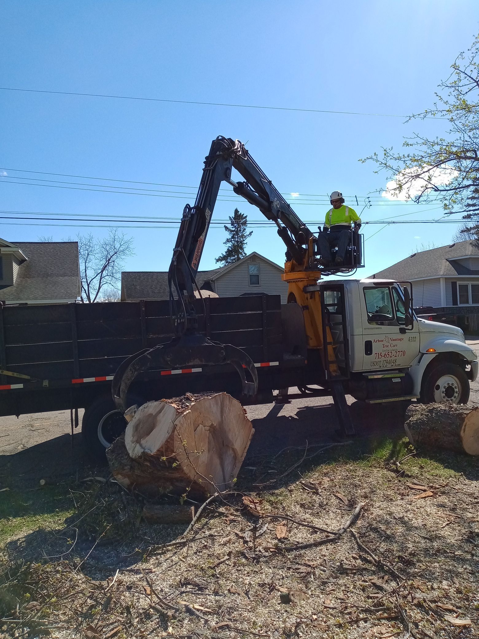 A man is standing on top of a truck with a crane attached to it.