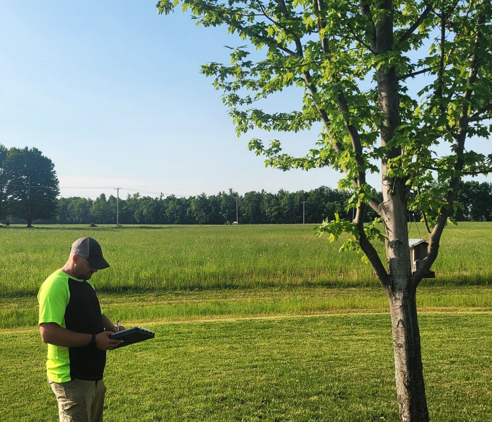 A man is standing in a field looking at a tablet