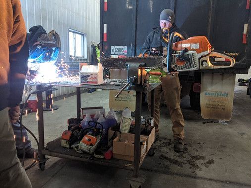 A man is standing next to a table with a chainsaw on it.