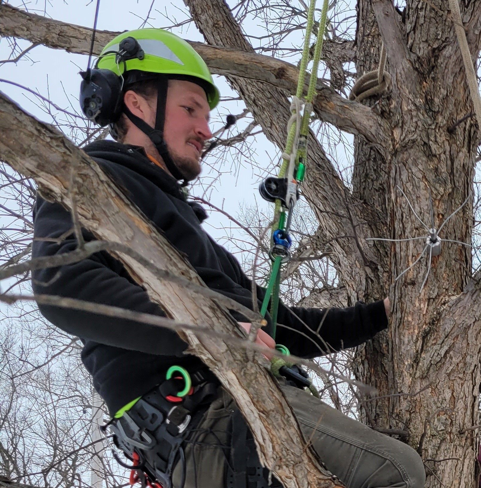 A man wearing a helmet and headphones is climbing a tree.