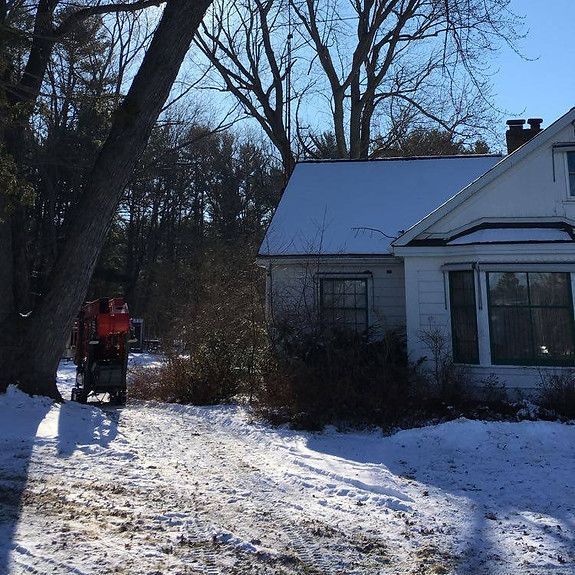 A snow blower is parked in front of a white house