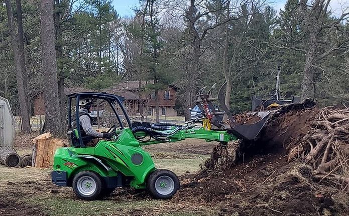 A man is driving a green tractor through a pile of dirt.