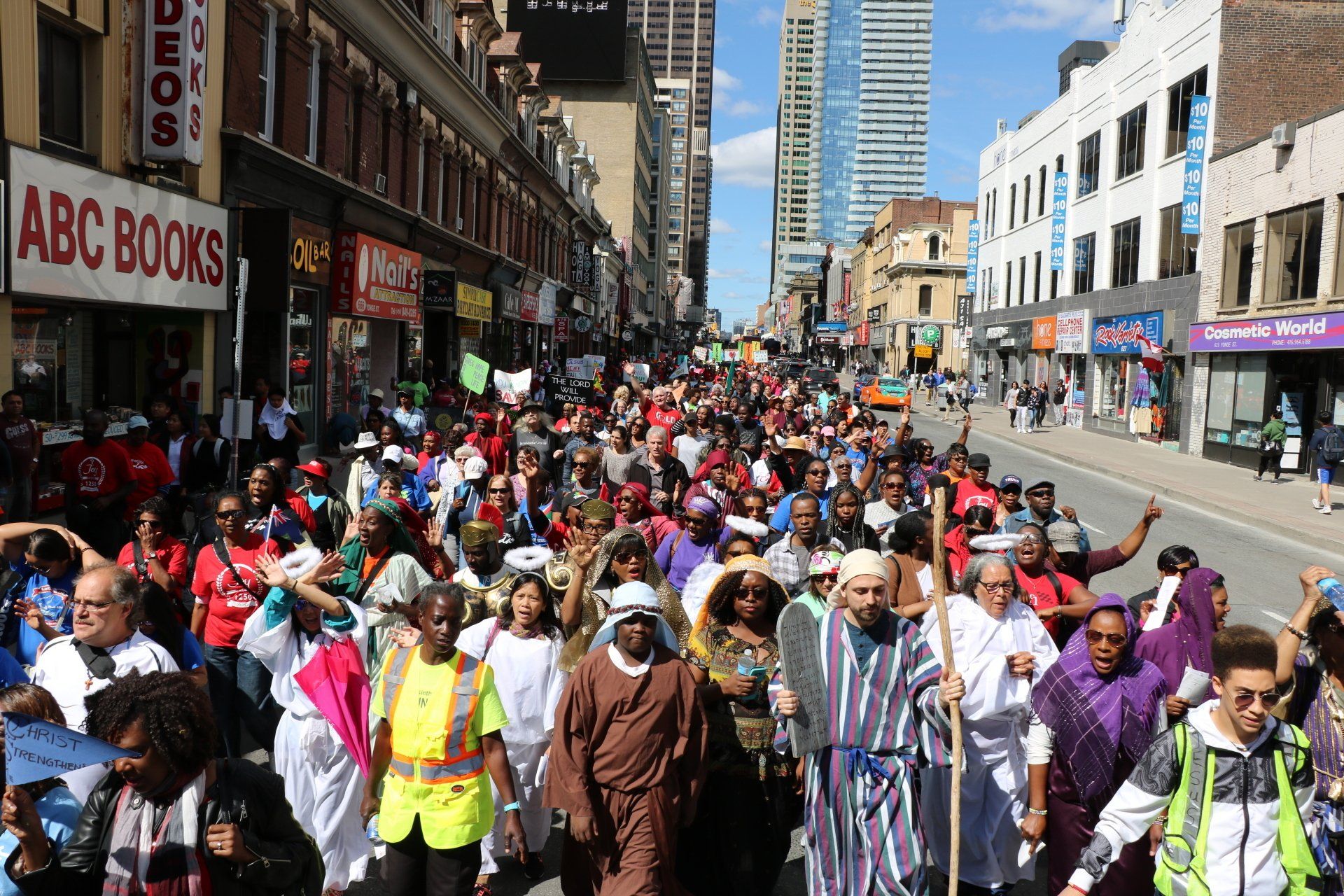 A crowd of people are walking down a street in front of abc books