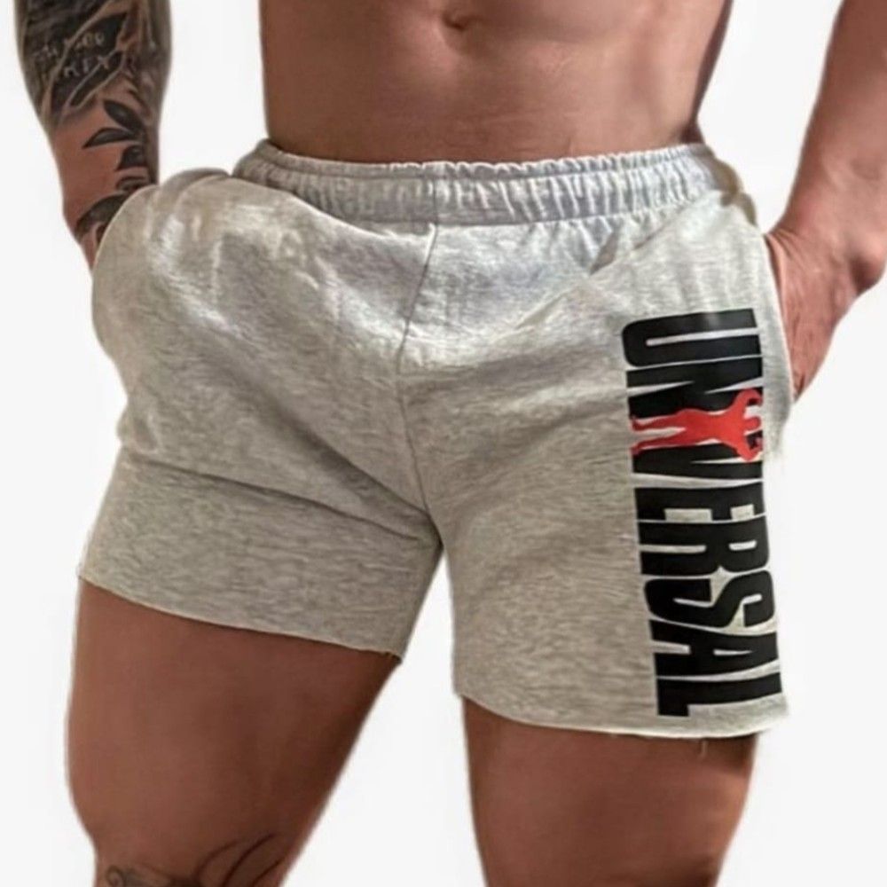Hombre vestido con pantalones cortos grises con el logo "UNIVERSAL", con las manos en los bolsillos.