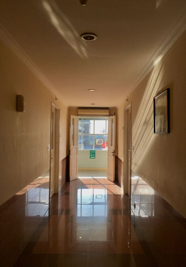 A long hallway with a green exit sign on the wall