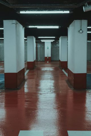 An empty parking garage with red and white pillars and a red floor.