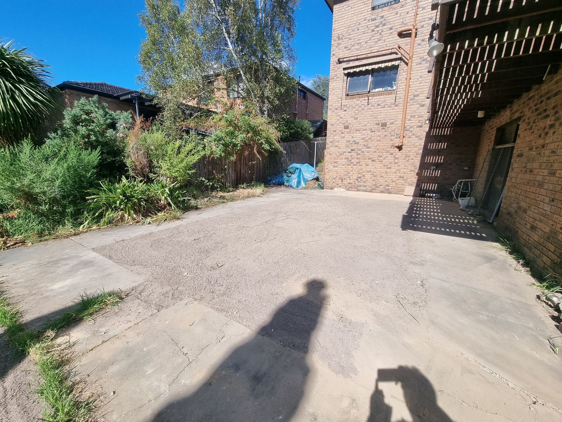 A paved outdoor area with a central gravel section adjacent to a brick building under a sunny blue sky  — All Over Pool Removals in Doncaster, VIC