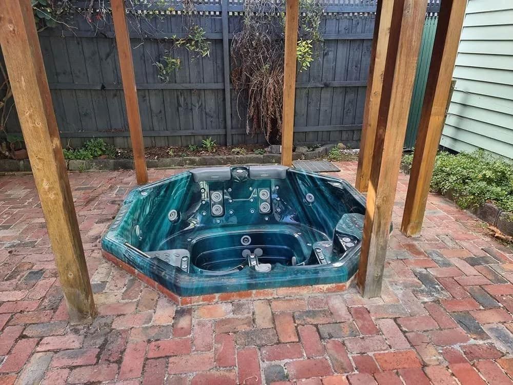 A Green Hexagonal Hot Tub Inside a Wooden Pergola, on a Brick Patio — All Over Pool Removals in Narre Warren South, VIC