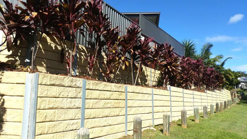 A Retaining Wall Made of Light-coloured Blocks, Topped With Red Plants — All Over Pool Removals in Doncaster, VIC