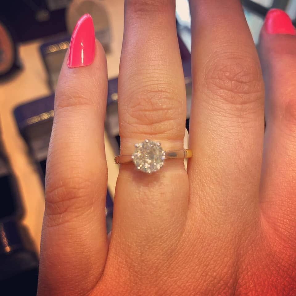 A woman with pink nails is wearing a diamond ring