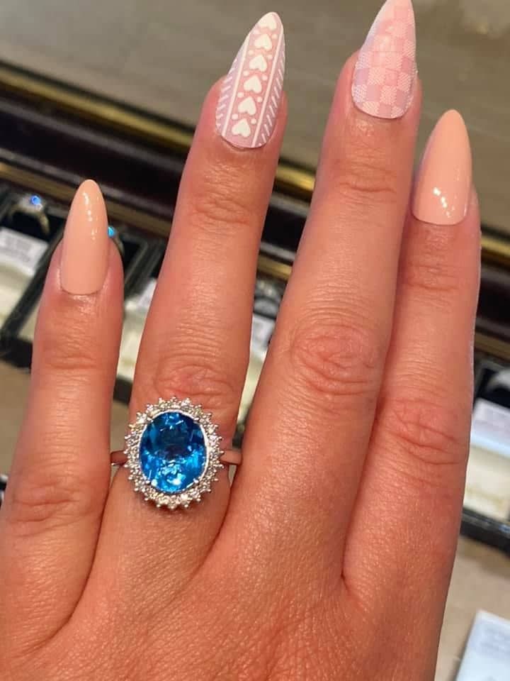 A woman is wearing a ring with a blue stone on her finger.
