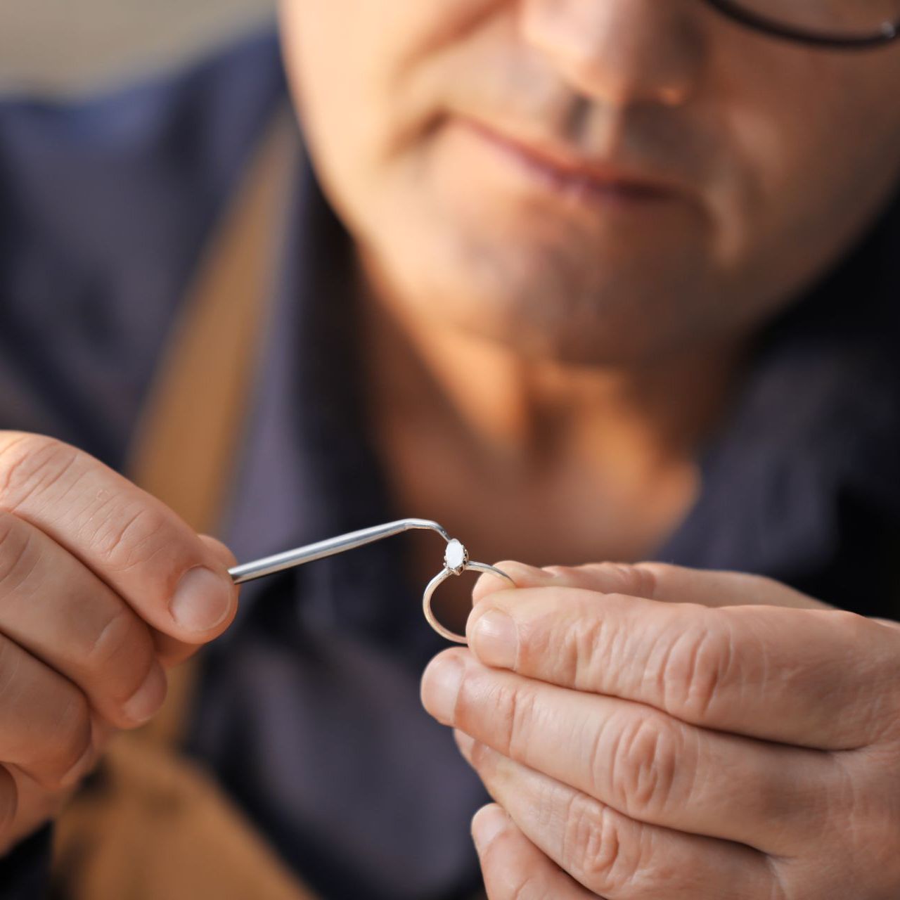 A man is working on a ring with a pair of tweezers.