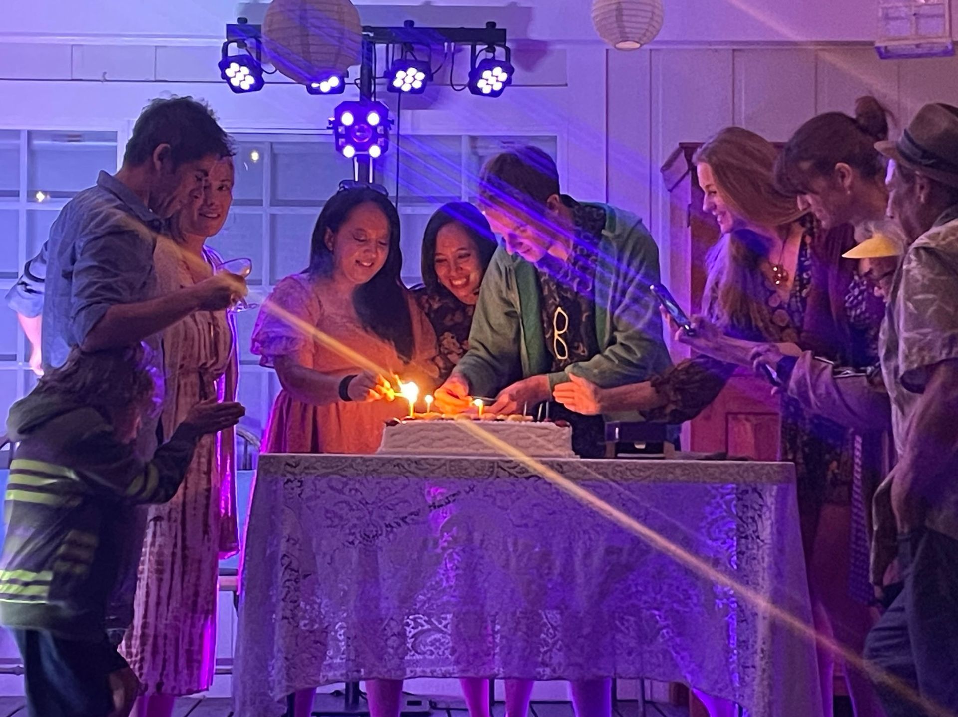 People lighting candles on a cake, celebrating in a brightly lit room.