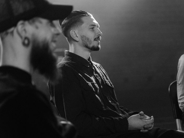 The photo captures a photo of two men attending a group coaching session aimed at wellness and personal growth.