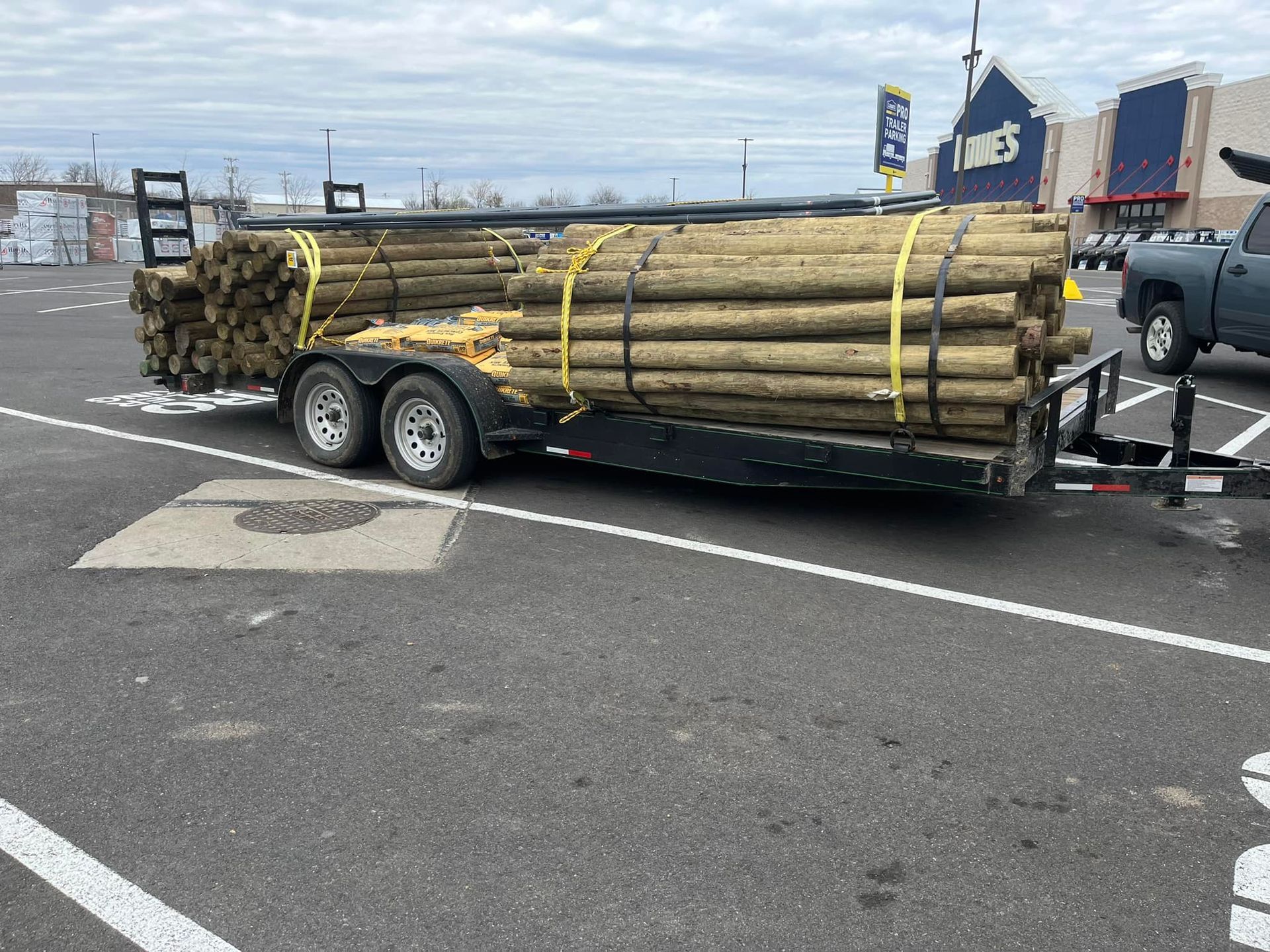 A trailer with a stack of wood on it is parked in a parking lot.