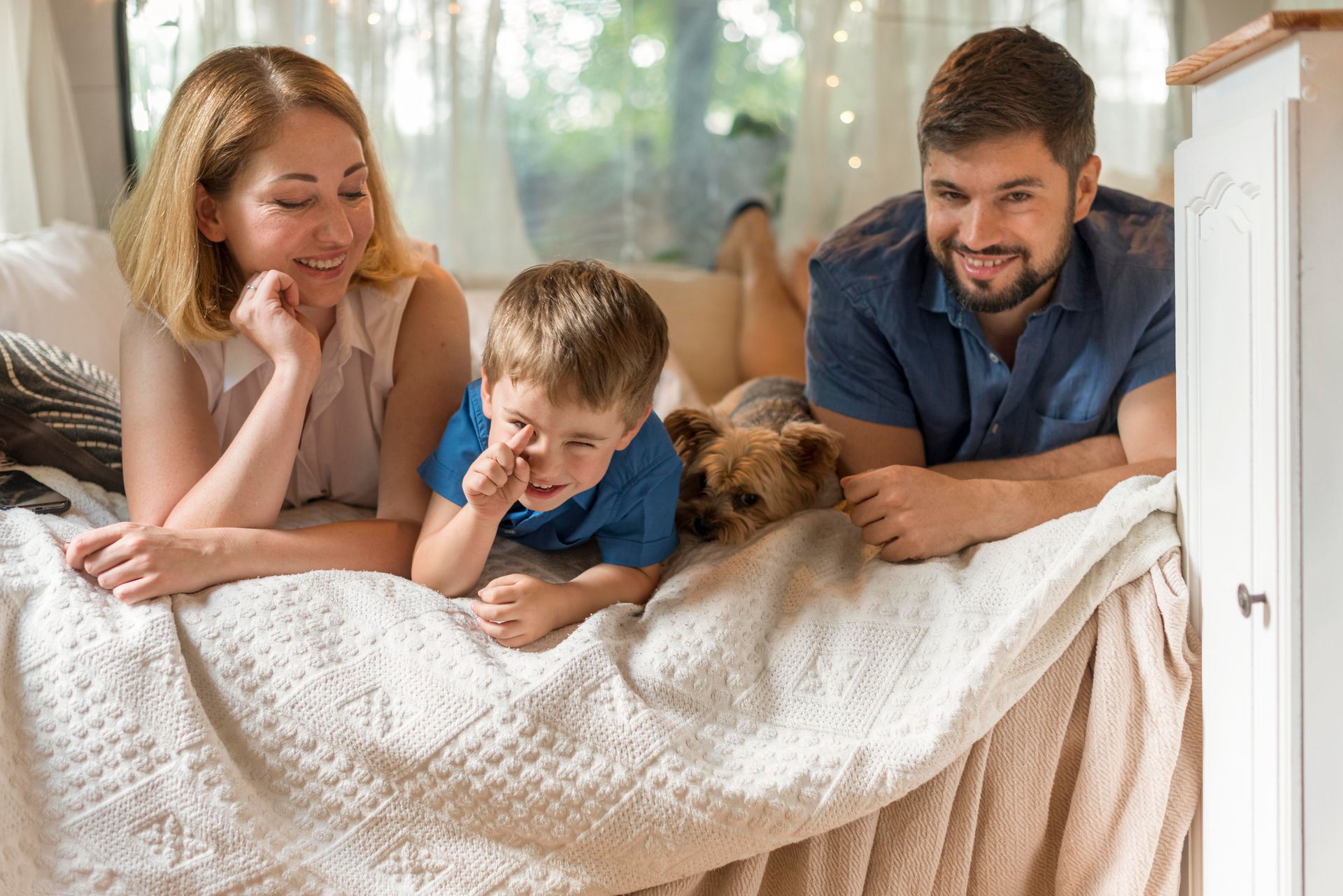 Family and dog relaxing on a bed in a camper.