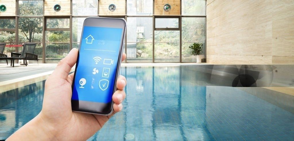A person is holding a smart phone in front of a swimming pool.