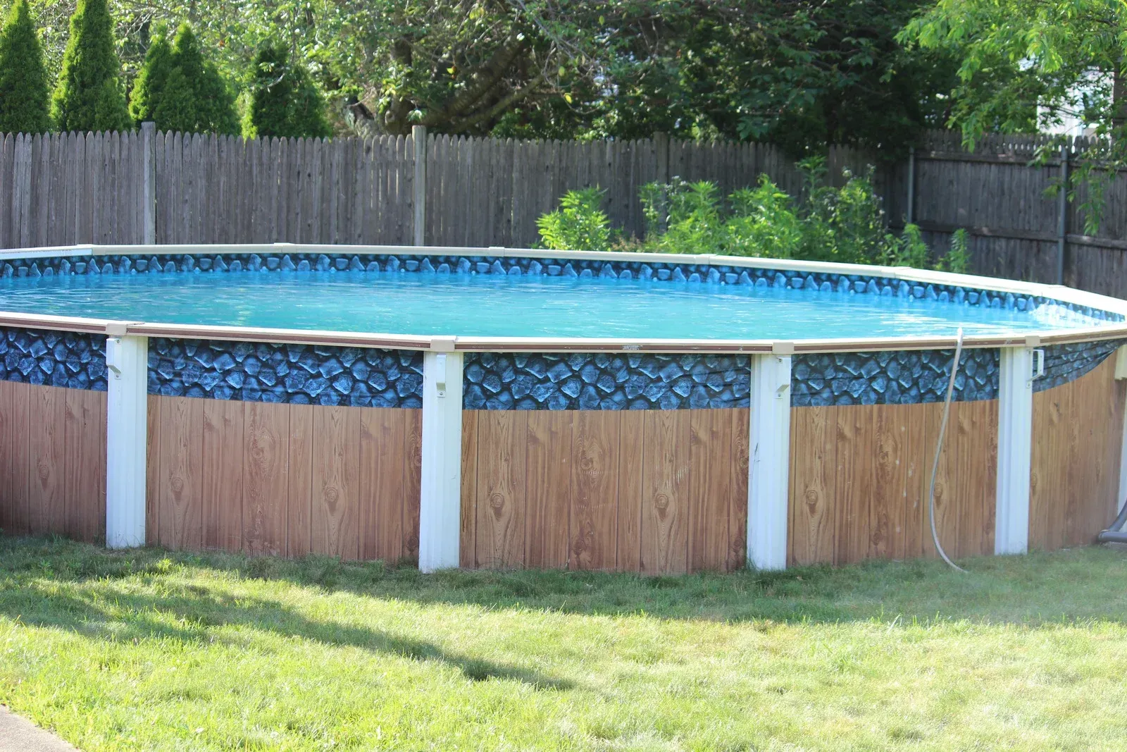 A large swimming pool is sitting in the middle of a lush green yard.