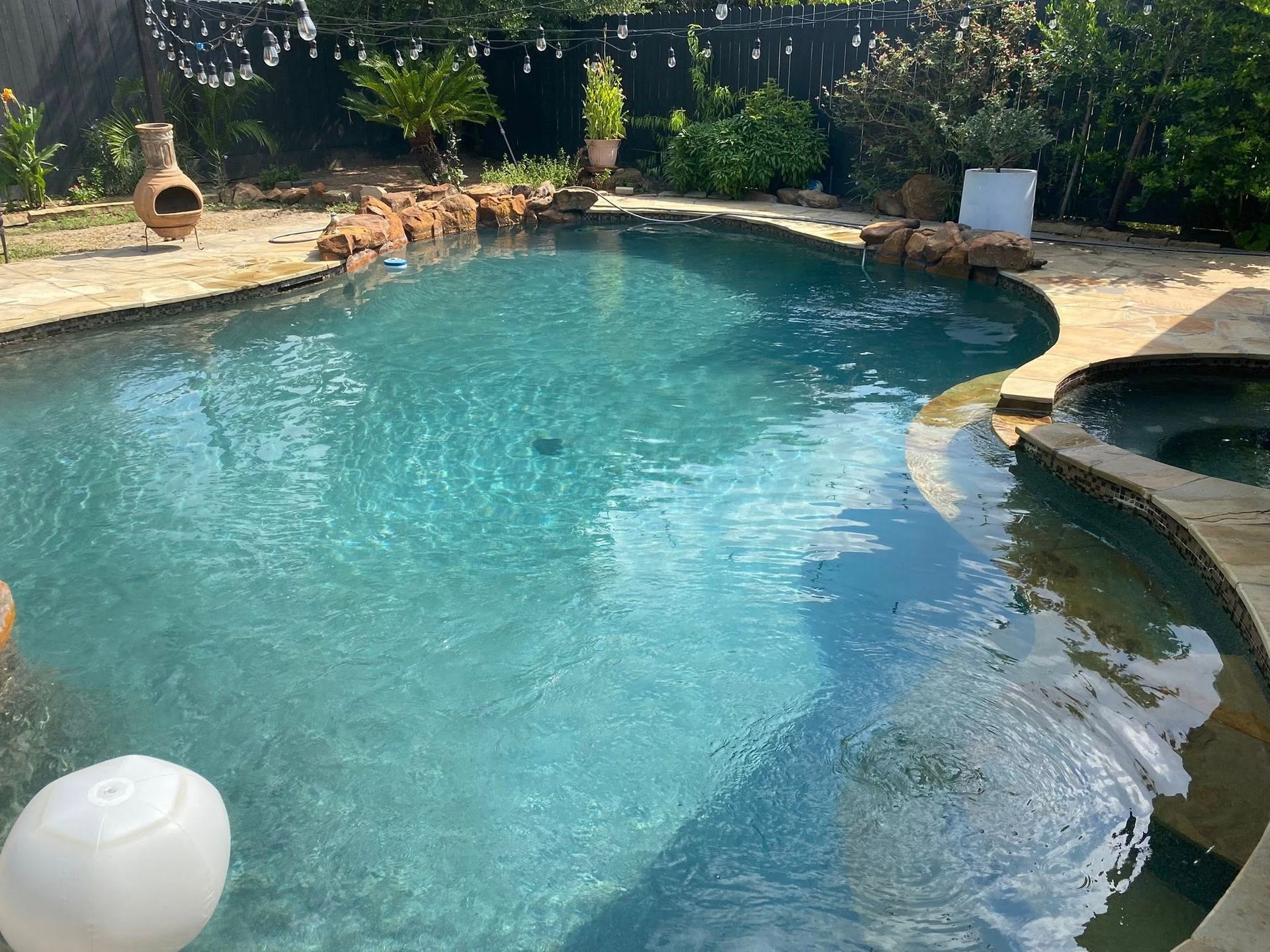A large swimming pool with a hot tub in the backyard.