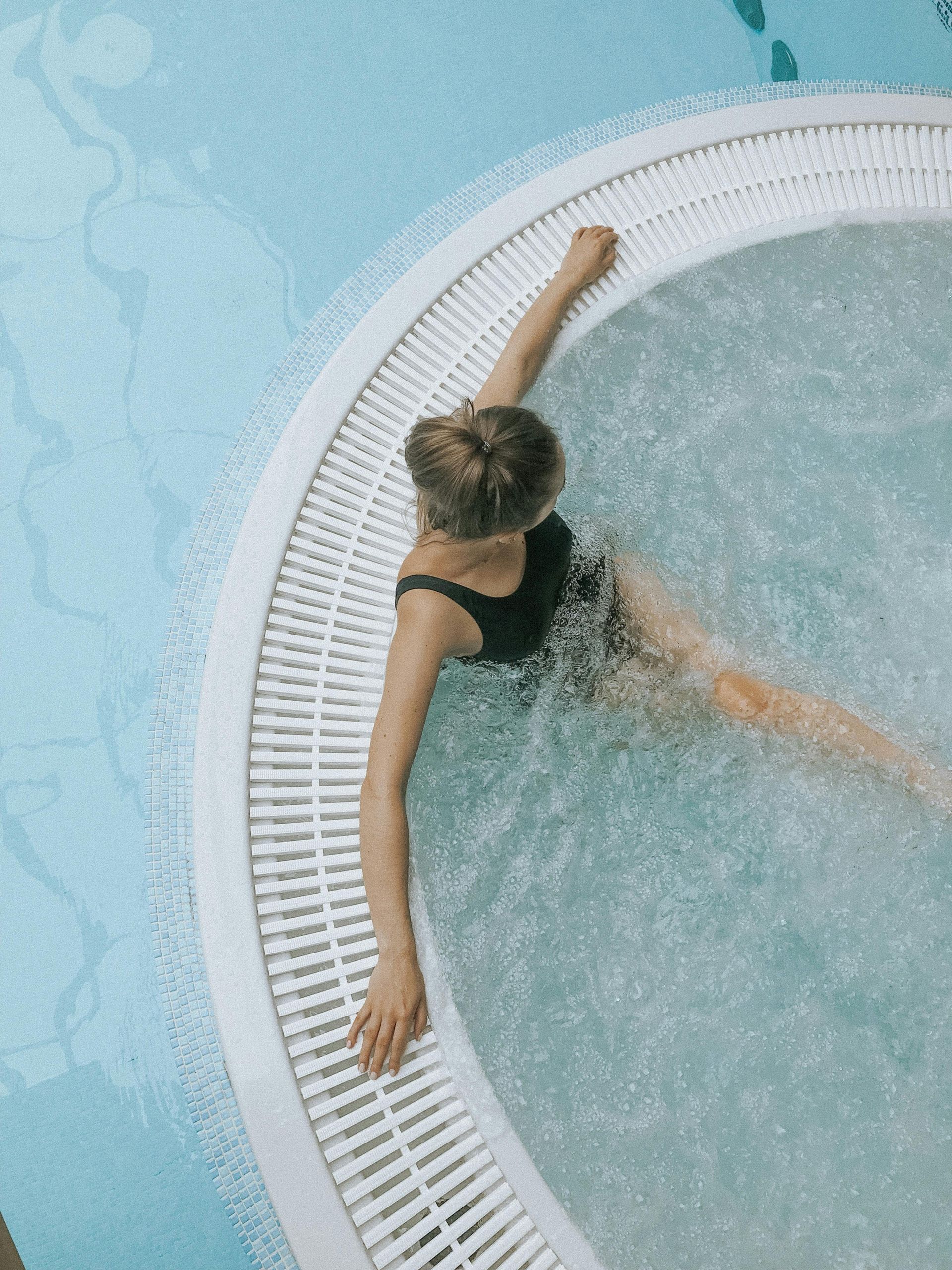 A woman is swimming in a hot tub in a swimming pool.