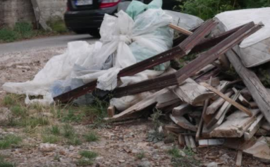 Junk in front yard that needs to be thrown away. Wood pieces , mattress, and bags