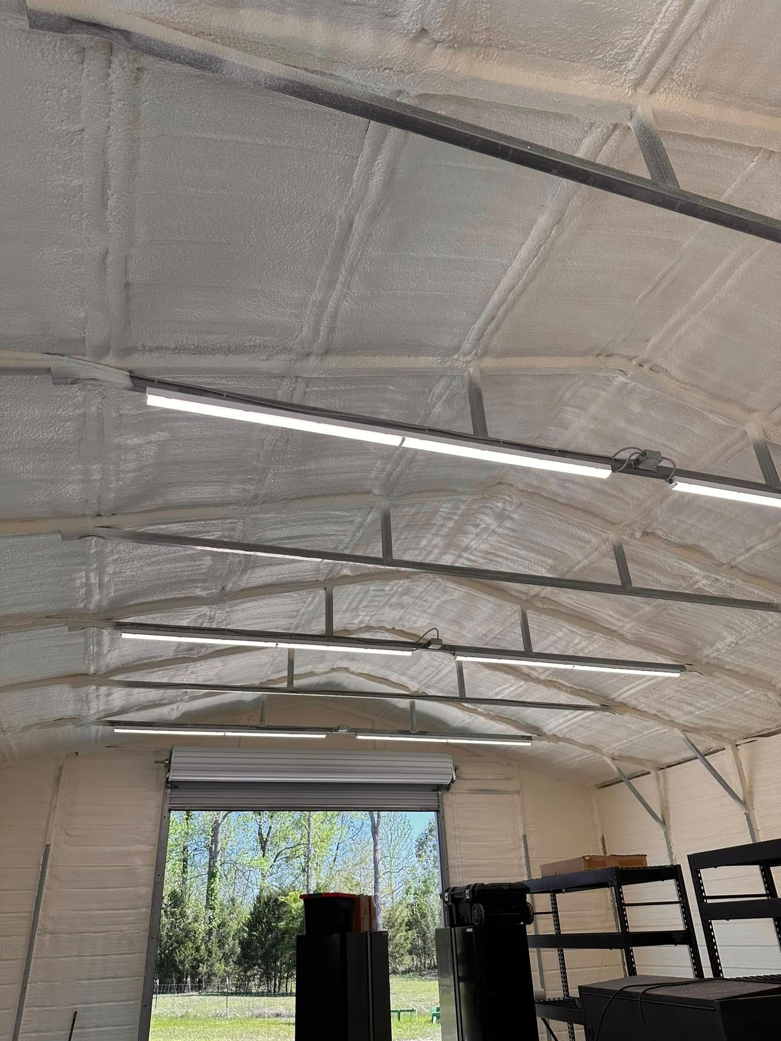 Interior of a garage with a white insulated ceiling, fluorescent lights, and shelves along the right wall