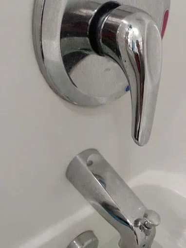 Chrome-colored bathtub faucet with lever handle and spout, against a white background.