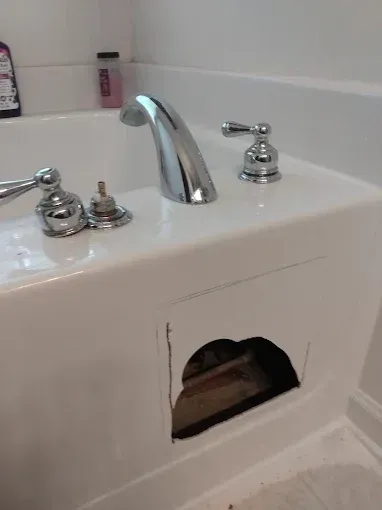 White bathtub with chrome fixtures, and a large opening in its side.