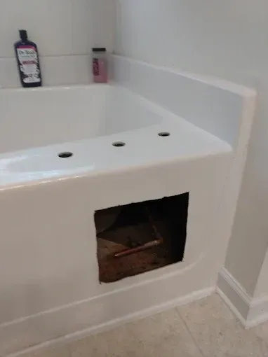 White bathtub with open access panel, plumbing visible.