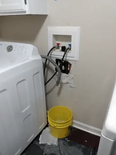 Washing machine next to water hookups in a wall. 