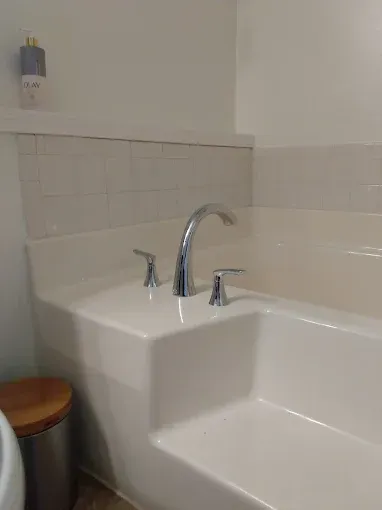 Bathtub with chrome faucet, two handles, and white tile. 