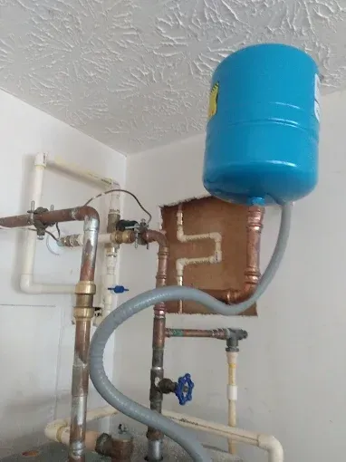 Blue water pressure tank connected to copper pipes and valves.