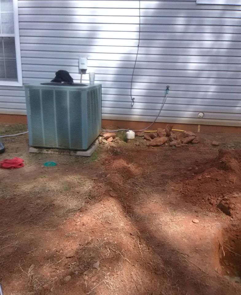 Air conditioner unit outside a house, on a concrete pad. 