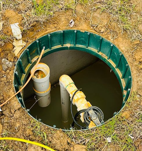Open septic tank, green rim, pipes visible inside.