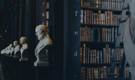 Rows of leather-bound books on polished wooden shelves in a warmly lit library. Rows of leather-bound books on polished wooden shelves in a warmly lit library.