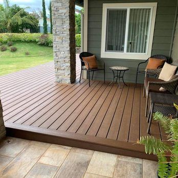 A composite wood deck with seating and small table.  A window is visible on a sage green wall.