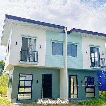 Duplex units with a white, teal, and gray exterior. Each unit has windows and a dark door, with balconies on the second floor.