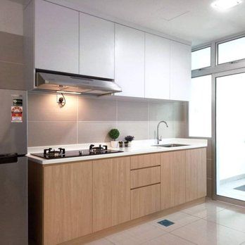 Modern kitchen with white upper cabinets and light wood lower cabinets, gas stove, sink, and a window.