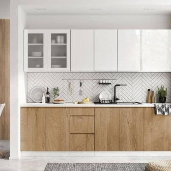 Modern kitchen with white and wood cabinets, herringbone tile backsplash, and stainless steel sink.