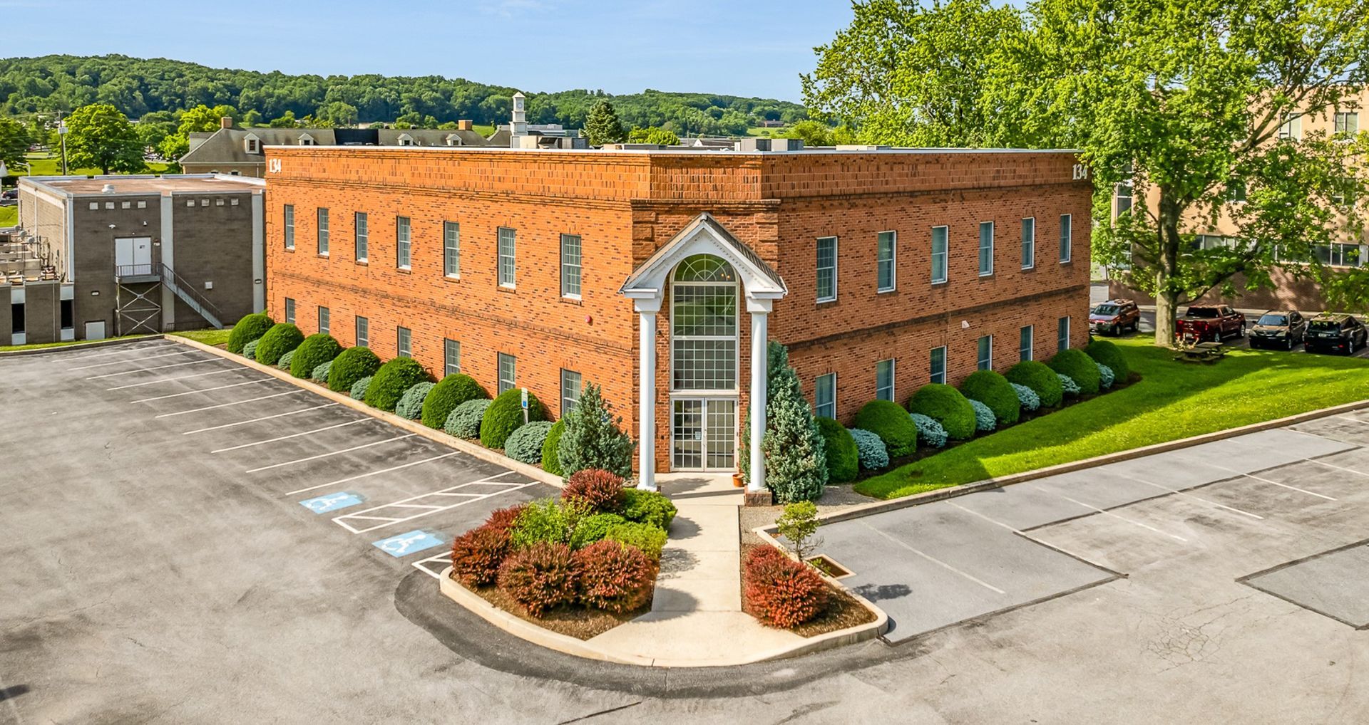An aerial view of a large brick building with a parking lot in front of it.