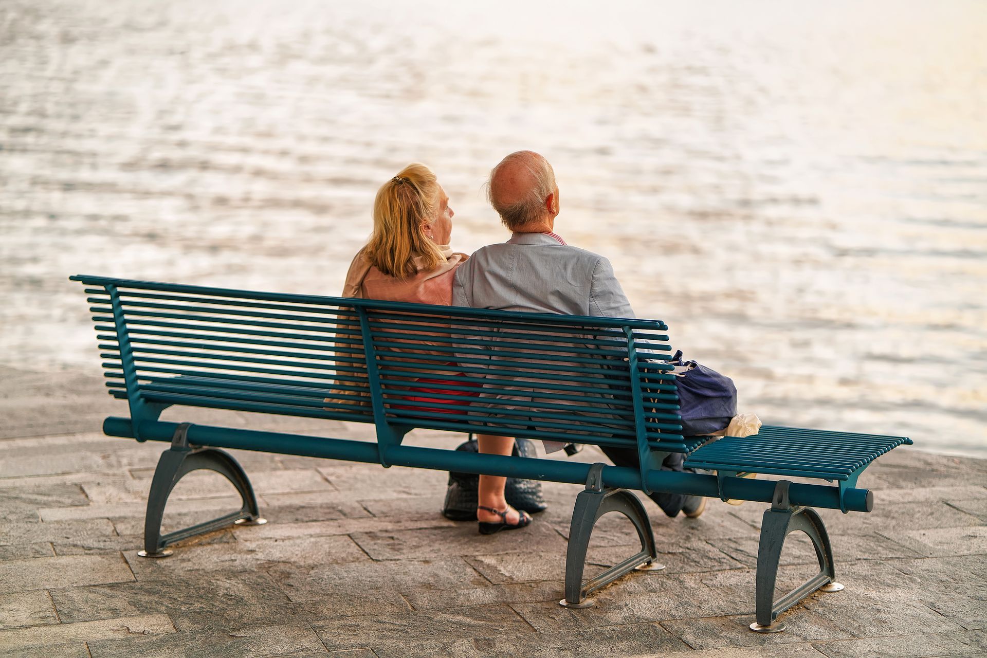 A man and a woman are sitting on a bench overlooking the water.