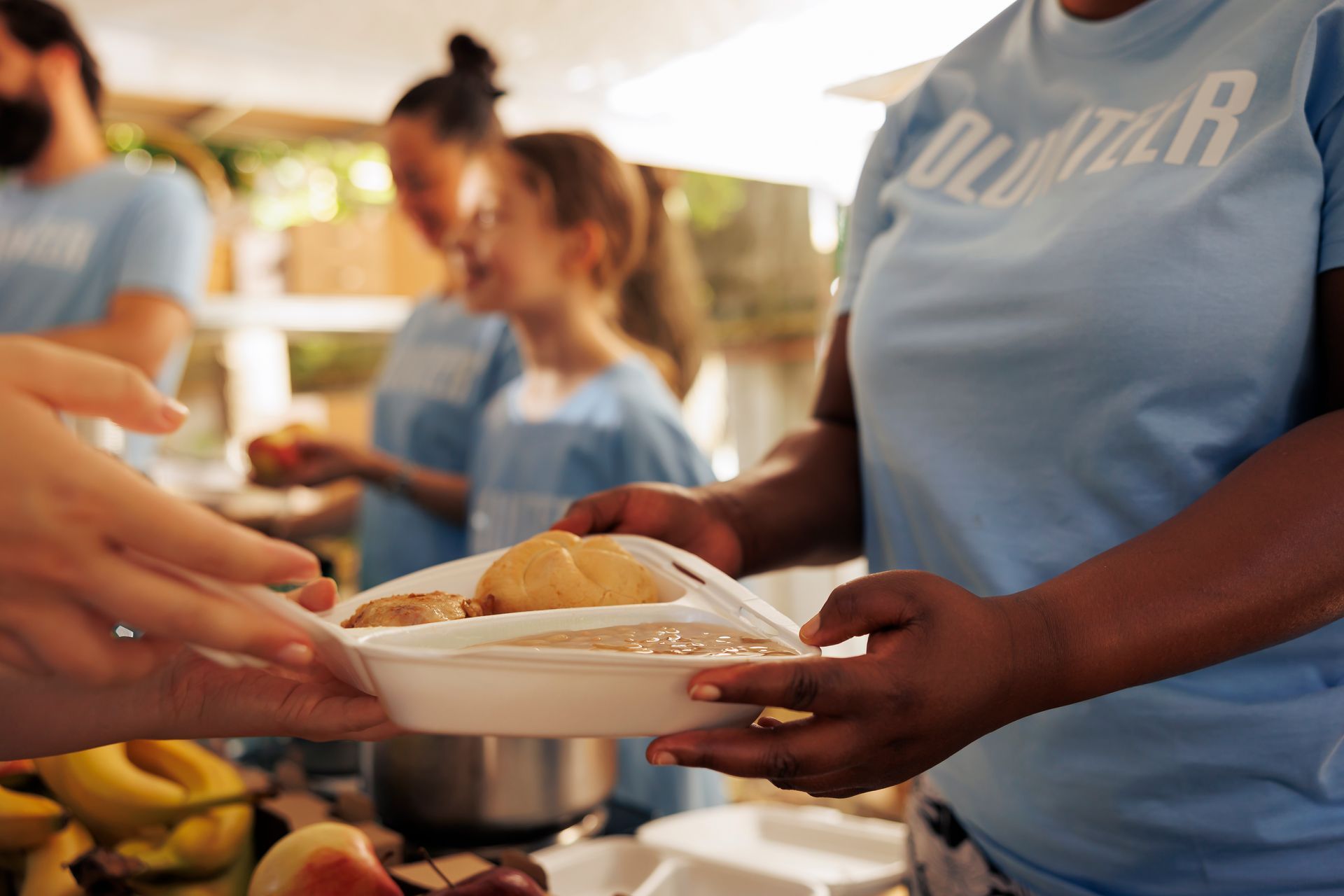 A woman in a blue shirt is serving food to another woman.
