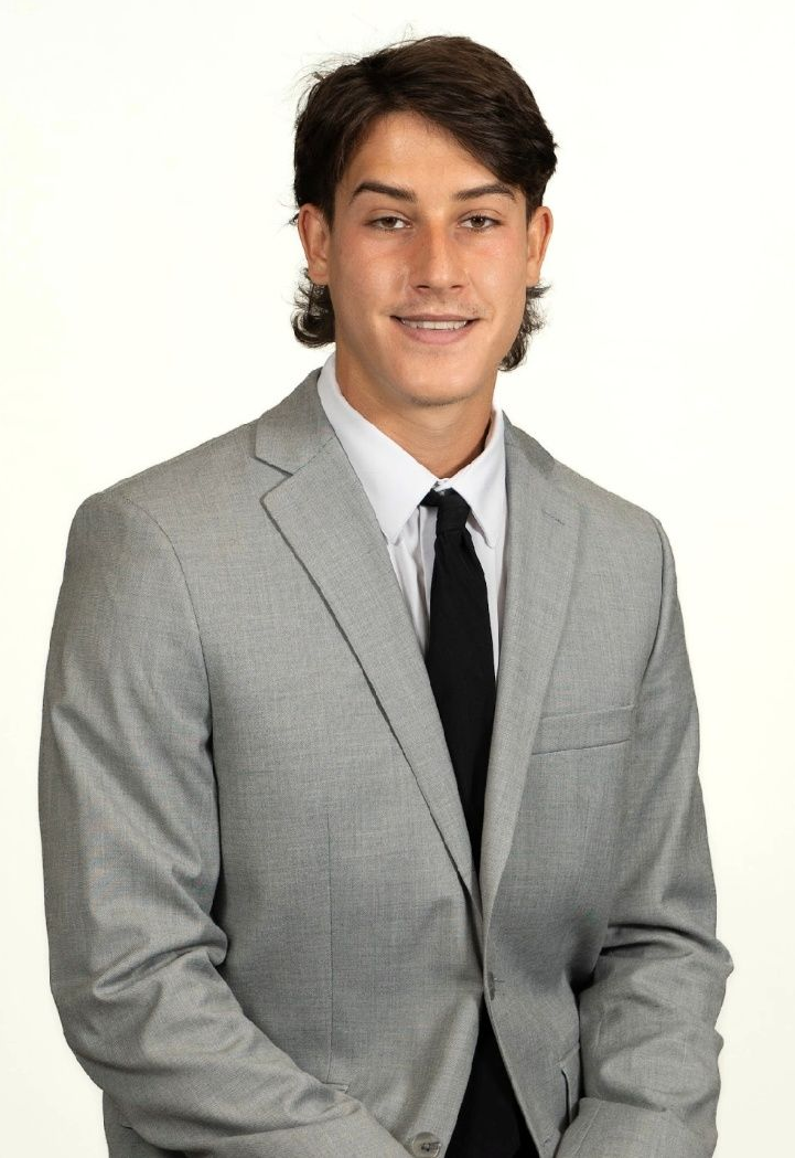 A young man in a blue suit and white shirt is smiling for the camera.