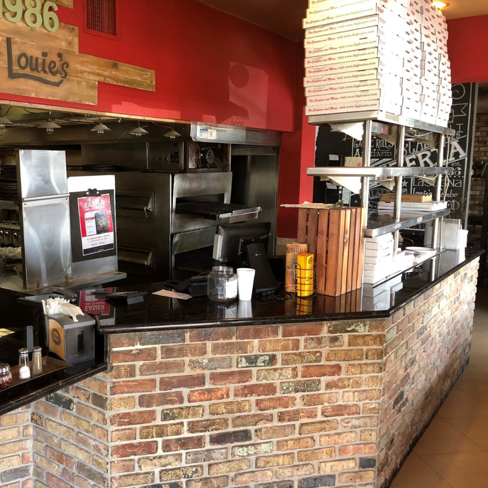 Big Louie’s Pizzeria interior with brick counter