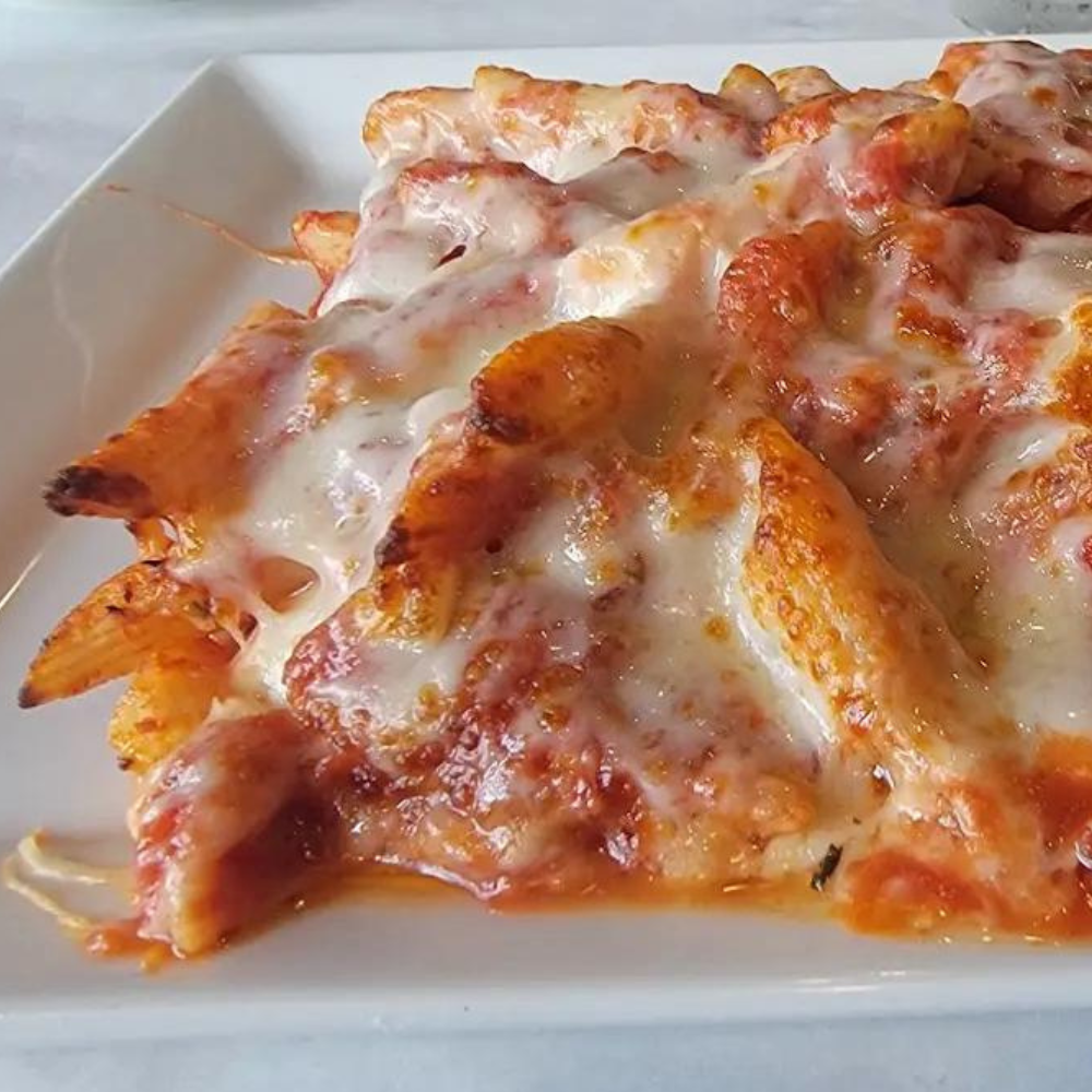 Big Louie’s Pizzeria baked penne pasta with melted mozzarella cheese, served on a white plate in Broward County, Florida