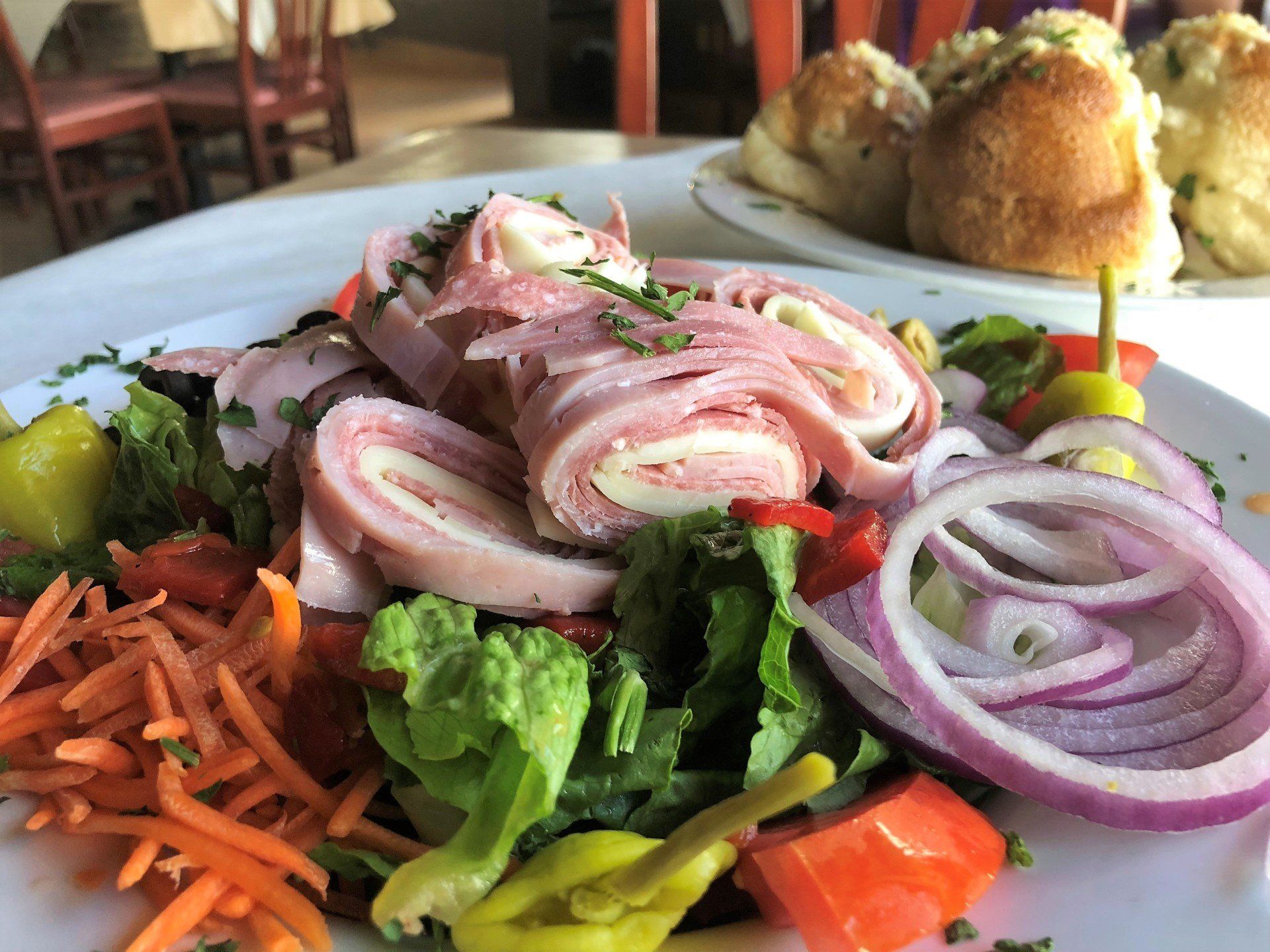 Salad with rolled ham and cheese, red onion, carrots, peppers, and rolls with garlic.