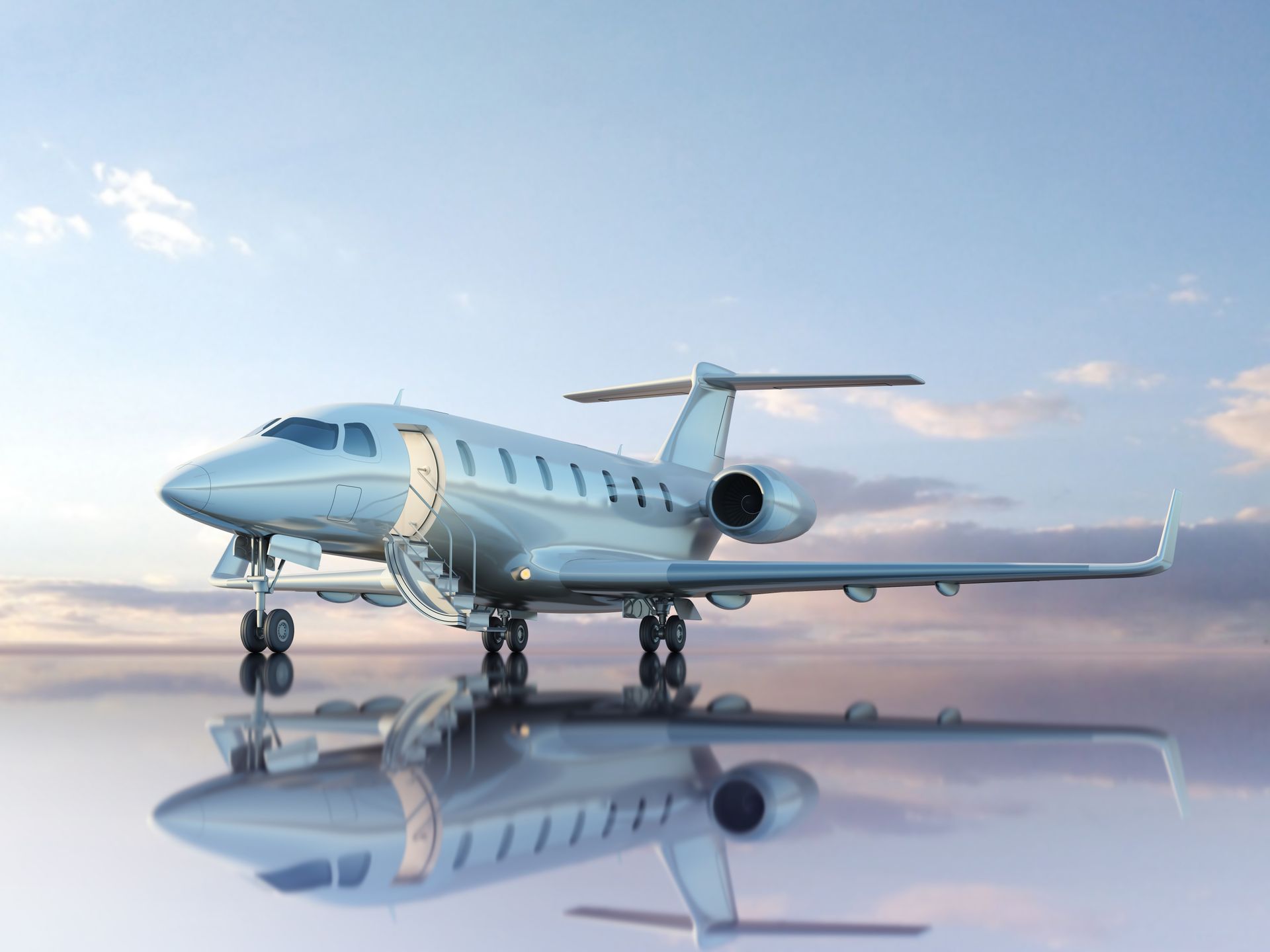 A silver private jet with open door sits on a reflective surface against a blue sky.