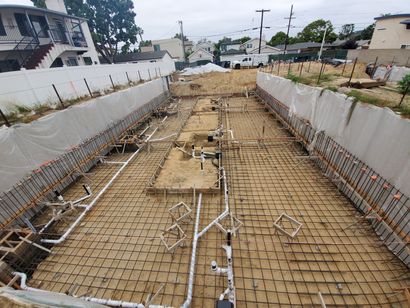 Construction site with rebar grid and white retaining walls along a trench